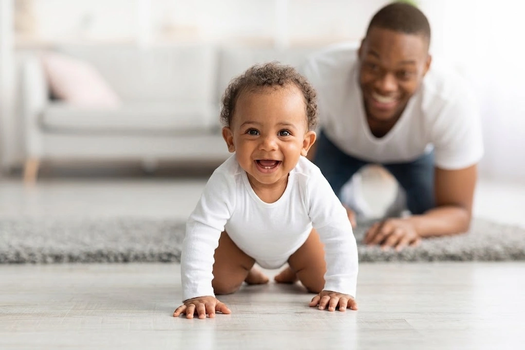 bebê engatinhando e sorrindo o pai observa os saltos de desenvolvimento do bebê.